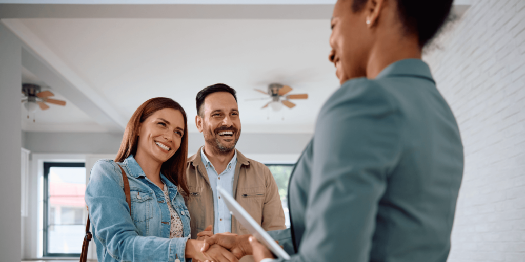 Smiling couple shaking hands with a property professional inside a bright, modern rental home, symbolising a positive landlord-tenant agreement and rental property management.